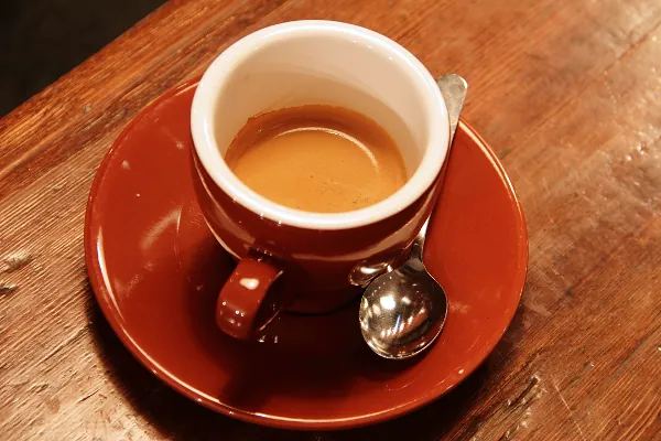 Espresso i en röd kopp på ett träbord